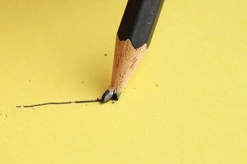 Drawing stroke with graphite pencil on yellow background, closeup