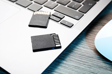 SD memory cards and laptop on wooden table, closeup