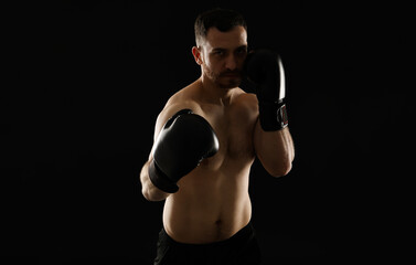Man in boxing gloves fighting on black background