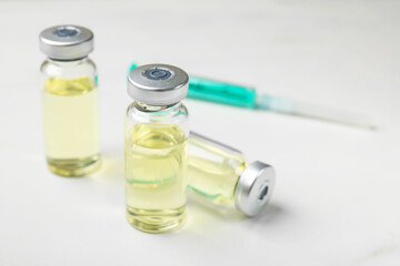 Hepatitis vaccine in glass vials and syringe on white table, closeup