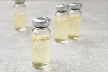 Hepatitis vaccine in glass vials on grey table, closeup. Space for text