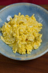 Egg salad made with cheese and relish, in a blue dish.