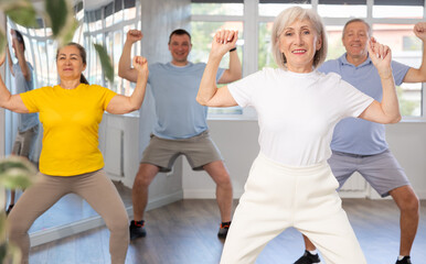 Fototapeta premium Group of aged people rehearsing sports dance in dance hall