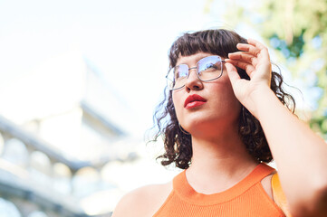 Real beauty of a confident and empowered young woman with wavy hair and red lipstick adjusting her...