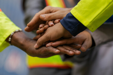 Team logistics workers in high visibility safety gear and hard hats discuss operations at a busy shipping container yard. Team multi nationality working together on site container warehouse.