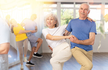 Couple of elderly man and elderly woman dancing twist in studio