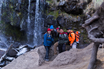 Group of hikers taking a selfie in front of a waterfall in the mountains