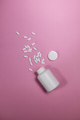 Blank white pill supplement bottle with spilled pills on a colorful background
