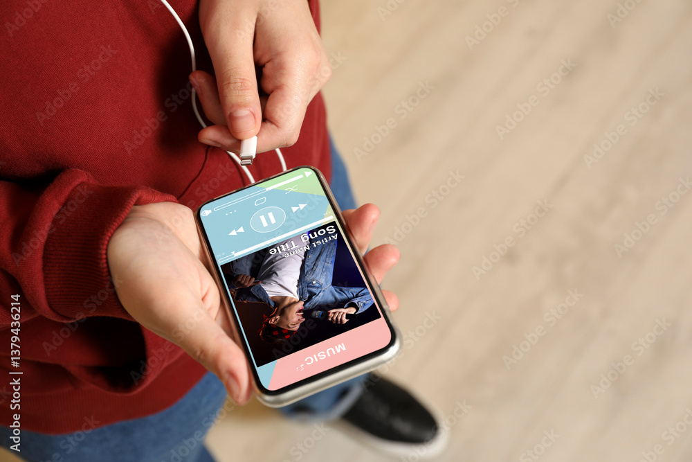 Poster man using mobile phone to listen to music indoors, closeup. open music player app on device screen