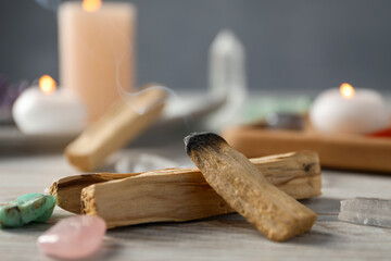 Smoldering palo santo stick and gemstones on wooden table, closeup