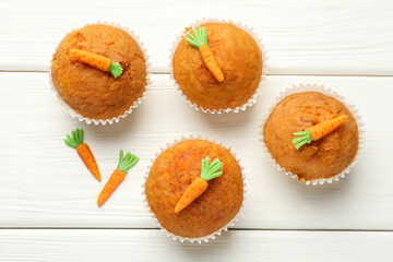 Tasty carrot muffins on white wooden table, flat lay