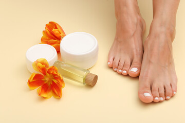 Pedicure. Woman showing toenails covered with nail polish, cosmetic products and flowers on beige...