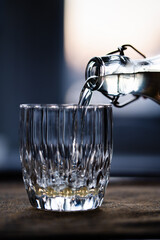 Poring mead from a flip-top bottle into a glass, in a dark room