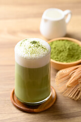 Matcha green tea with foam milk in glass on wooden background