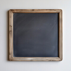 Fototapeta premium a square, dark gray chalkboard set within two wooden frames. The inner frame is light brown and the outer frame is a slightly darker beige.