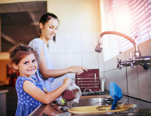 Mother, girl and portrait for cleaning dishes in home, learning hygiene and happy child in kitchen....