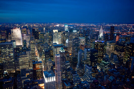  aerial view of the illuminated new york city skyline at night, featuring the chrysler building