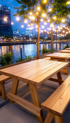 Serene waterfront patio with wooden picnic tables, string lights, and city skyline at dusk