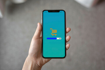 Shopping Cart Loading on Smartphone Screen Held by Hand Indoors
