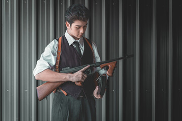 Handsome man holds an ancient machine gun, ready to shoot in self-defense. Retro Fashion...