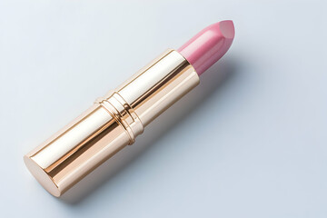 Obraz premium Pale pink lipstick in gold tube on light background