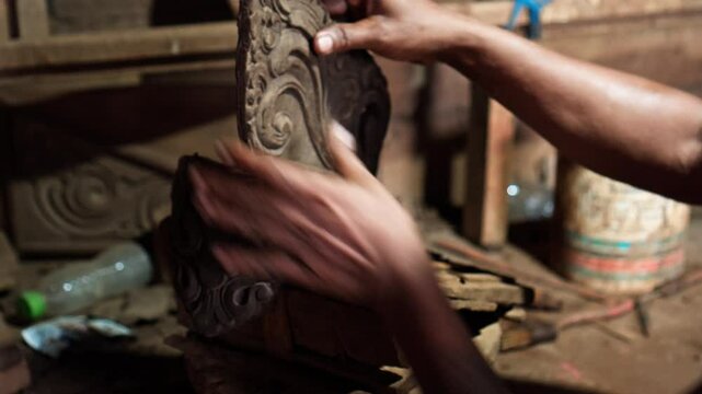 Dirty hands of worker making clay statue in Balinese style in dark workshop
