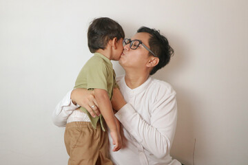 Fototapeta premium Father kisses 3 year old child as an expression of affection on Eid al-Fitr