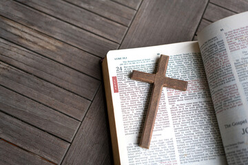 Wooden crucifix cross on top of Luke 24 of the Holy Bible, mentioning the Resurrection of Jesus...