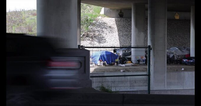 Compton, California, USA - April 2, 2025: A homeless encampment occupies a space below the 91 Freeway.