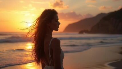 Serene beach at sunset with gentle ocean waves and a mountain range in the distance, featuring warm hues of orange, pink, and yellow, and a person in a sleeveless top enjoying the view.