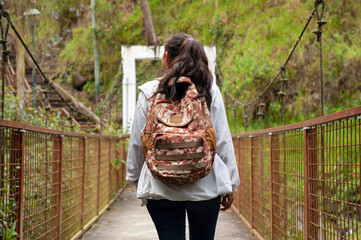 A solo traveler crosses a suspension bridge, embracing natures beauty and adventure with a backpack