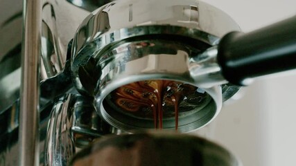 Pouring coffee stream from professional machine in cup. Barista man making double espresso, using filter holder. Flowing fresh ground coffee. 