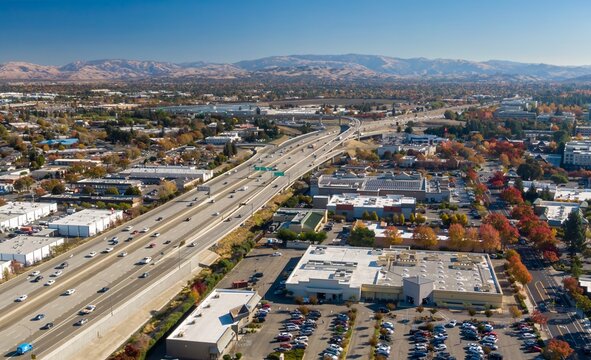 Aerial view of a busy Interstate 680 with cars moving through a suburban area with mountains in the background, Dublin, California, USA. Illustrates transportation and urban planning.