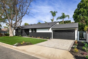 Modern black and white home with two-car garage and fresh landscaping
