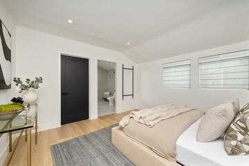 A minimalist bedroom with neutral tones, modern decor, and an en-suite bathroom.
