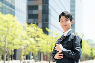 オフィスビルを背景に立つエンジニアの男性