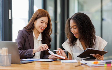 Fototapeta premium Two business women or an accountant team are analyzing data charts, graphs, and a dashboard on a laptop screen in order to prepare a statistical report and discuss financial data in an office 