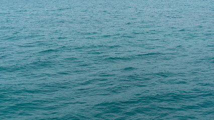 Water of ocean with gentle ripples. Water appears to be a consistent teal or blue green color suggesting a sea or large body of water. Focus is on the water texture and subtle movement.
