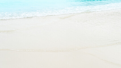 Gentle waves of the sea hitting the soft colored beach. Travel on the sea beach on day time.