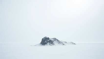 Lone snow-covered rock formation rising from vast frozen plain under pale winter sky	
