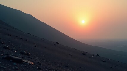 Desert valley with winding stream at sunset between silhouetted hills	