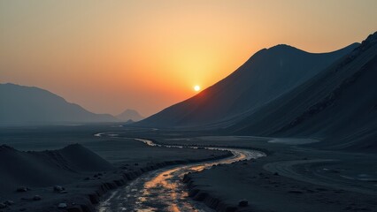 Desert valley with winding stream at sunset between silhouetted hills	
