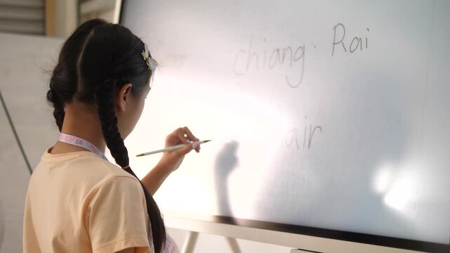 Southeast Asian Girl Writing on Digital Board During Tutoring Session &ndash; Modern Learning and Education Technology Concept