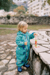 Little girl dipping a soap bubble stick into a bottle of liquid