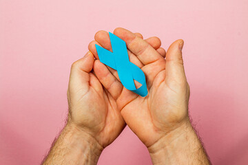 Supporting cancer awareness with blue ribbon held in hands for health hope