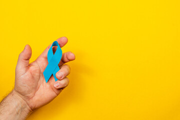 Holding a blue ribbon symbolizing cancer awareness and support initiatives