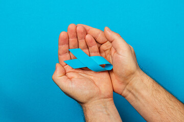 Raising awareness for cancer prevention with a blue ribbon in hands