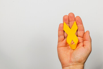 Holding a yellow ribbon symbolizes hope and support for cancer awareness