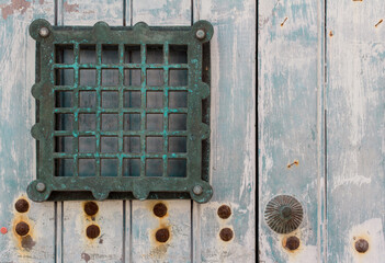 Small barred window in a weathered blue door.