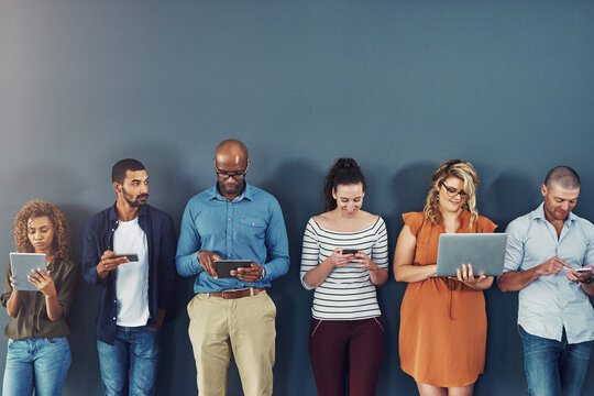 Technology, connectivity and team of business people at wall together on phone, tablet or laptop. Internet, communication and creative employees with contact on website, digital network or mobile app